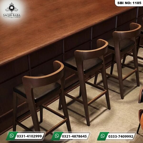 Solid walnut finish counter table with modular paneling lined with premium curved wooden bar stools by Saqib Baba Interior