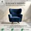 A premium navy blue velvet wingback chair with a deep-cushioned seat and a modern gold swivel cross-base, set in a luxury marble interior.